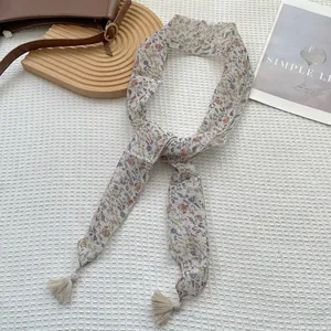 Dettaglio di foulard twilly in chiffon a fiori con nappe beige su sfondo bianco