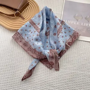 Detail of silk square scarf featuring paisley pattern and polka dots on blue and red fabric