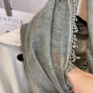 Gros plan sur l'écharpe en lin vert sauge avec broderie dentelle et texture respirante