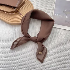 Detail view of a dark brown silk scarf with fine stitching and a metal brand tag