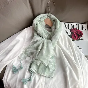 Light green floral cotton linen scarf with elegant tassels on a white shirt