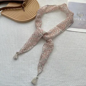Dettaglio di sciarpa a fiori paisley con piccoli accenti di nappe in beige chiaro