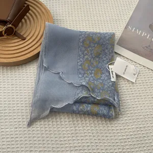 Close-up of narrow striped floral silk scarf with stitched edges and brand tag