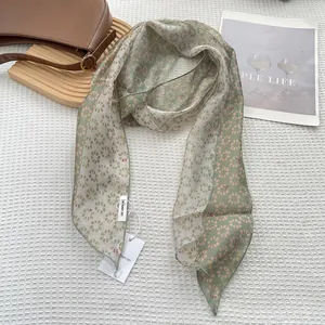 Detail of floral skinny silk scarf with 'be keen on' tag on white waffle texture fabric