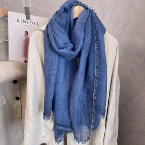 Vue détaillée d'une écharpe en coton et lin bleu marine avec bordures à pompons