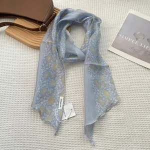 Detail of light blue striped silk scarf with floral patterns on a white background