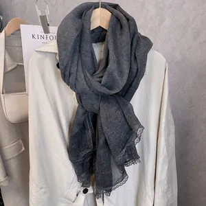Detail of dark charcoal cotton linen scarf featuring delicate lace trim on a hanger