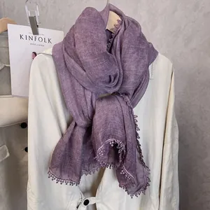 Détail d'une écharpe lilas en coton et lin avec dentelle au crochet et pompons perlés