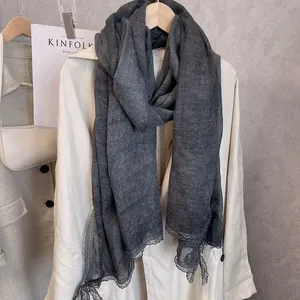 Detail of dark grey cotton linen scarf with elegant lace trim hanging on wooden hanger