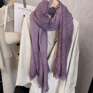 Détail d'une écharpe en coton et lin violet avec dentelle élégante sur un manteau beige