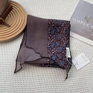 Detailed view of striped narrow silk scarf with blue vintage floral pattern and tags