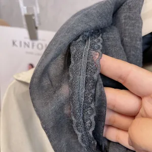 Close-up of dark grey cotton linen scarf featuring delicate lace edges and sheer knit fabric
