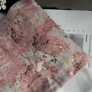 Detailed macro view of pink and white scarf with golden foil leaf patterns and texture
