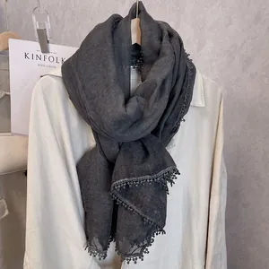 Détail d'une écharpe en coton et lin gris foncé avec bordure délicate en dentelle pompon