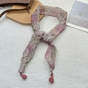 Dettaglio della sciarpa floreale con motivi lavanda e nappe rosa sulle estremità