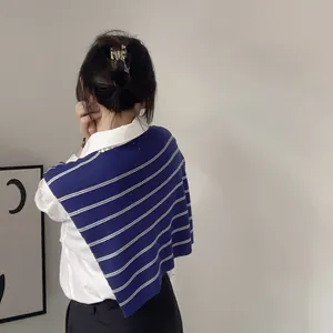 Detail of blue and white striped knit shawl layered over a white collared shirt