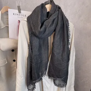 Détail d'une écharpe en coton gris foncé avec bordure décorative en dentelle