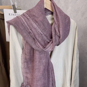 Detailed close-up of purple linen scarf with intricate floral lace trim on white shirt