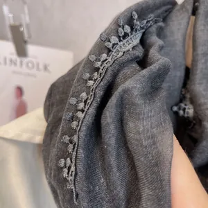Vue détaillée d'une écharpe en lin gris foncé avec bordure en dentelle brodée délicate