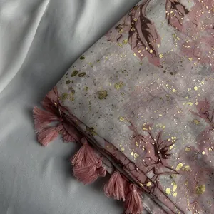Macro detail of pink floral chiffon scarf featuring gold foil prints and silk tassels