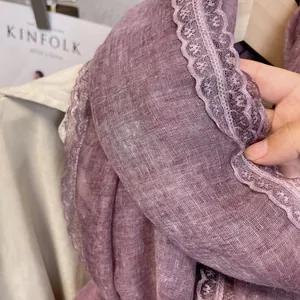 Close-up of thin mulberry purple linen scarf with delicate lace edge and breathable texture