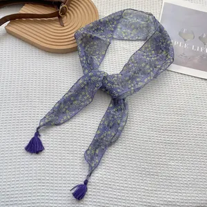 Dettaglio della sciarpa floreale in seta viola con motivi gialli ed eleganti nappe decorative