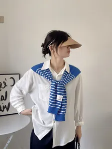 Detail of a navy blue and white striped knit shawl layered over a white shirt