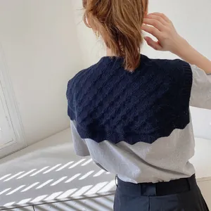 Rear view of navy blue cable knit faux collar shawl layered over a grey shirt
