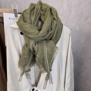 Detail of sage green cotton linen scarf featuring delicate lace trim and woven texture