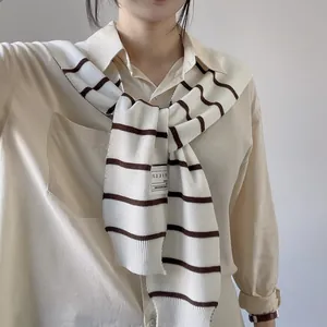 Close-up of striped knit shawl layered over a white collared shirt for a modern look