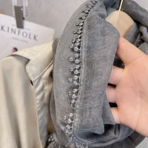 Gros plan d'une écharpe en coton et lin gris avec bordure en dentelle et texture douce