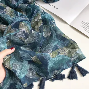Detail of navy blue cotton linen scarf with green leaf patterns and tassel ornaments