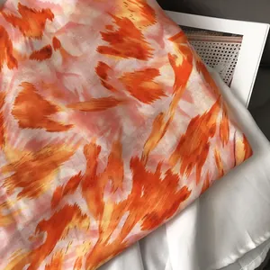 Close-up of lightweight linen-feel scarf with orange and pink graffiti tie-dye pattern