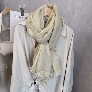 Close-up of beige cotton scarf featuring elegant floral lace trim and delicate tassels