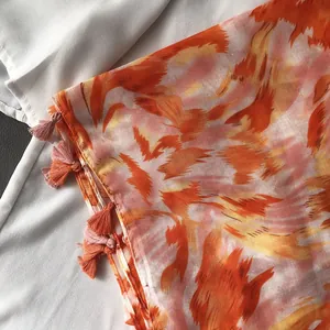 Detail of cotton-linen scarf with orange graffiti print and fringe tassels