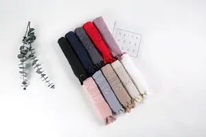 Close-up of assorted cotton linen scarves with geometric embroidery and fringe tassels