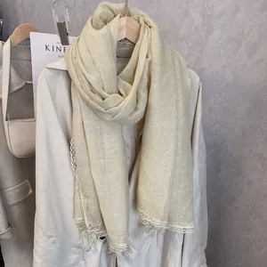 Close-up of cream cotton scarf featuring delicate white lace trim and bow knot detail