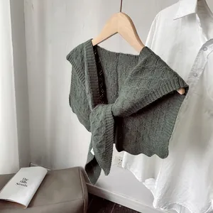 Close-up of dark green knitted shawl with cable stitch pattern and scalloped edges
