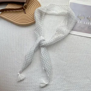 Dettaglio di un foulard in seta bianca a pois neri con nappe bianche sfrangiate sui bordi