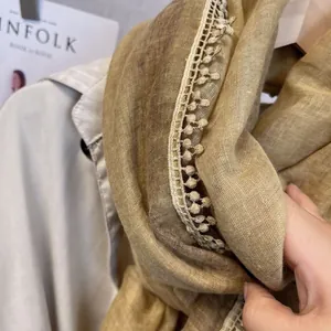 Détail d'une écharpe en lin doux avec bordure en dentelle à pompons et texture de tissu