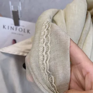 Detail shot of beige cotton linen scarf featuring elegant wavy lace trim edges and soft texture
