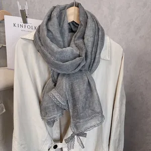 Detail of grey cotton linen scarf with elegant lace trim and bow knot decoration