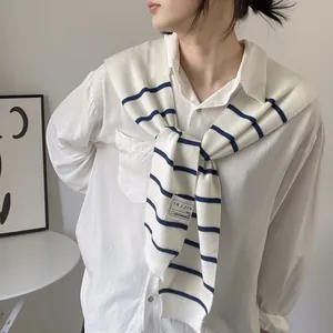 Detail of nautical navy striped knit shawl over white long-sleeve cotton shirt style
