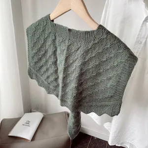 Macro detail of dark green knit shawl featuring hollow patterns and wavy scalloped hem