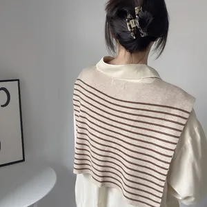 Close-up of a beige and brown striped knit shawl draped over a classic beige blouse