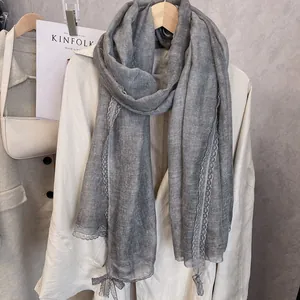 Close-up of elegant grey scarf with delicate floral lace trim and bow on a trench coat