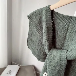 Detail of dark green knit shawl featuring classic cable stitch and ribbed neckline texture
