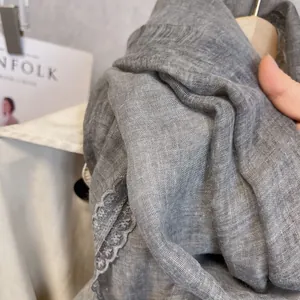 Close-up of grey linen scarf texture featuring delicate white lace edge detailing