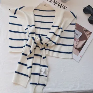 Detail of blue and white striped knit shawl with brand label on soft fabric background