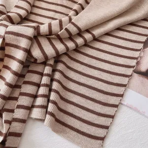Elegant beige and brown striped knitted shawl wrap for women over a white textured background